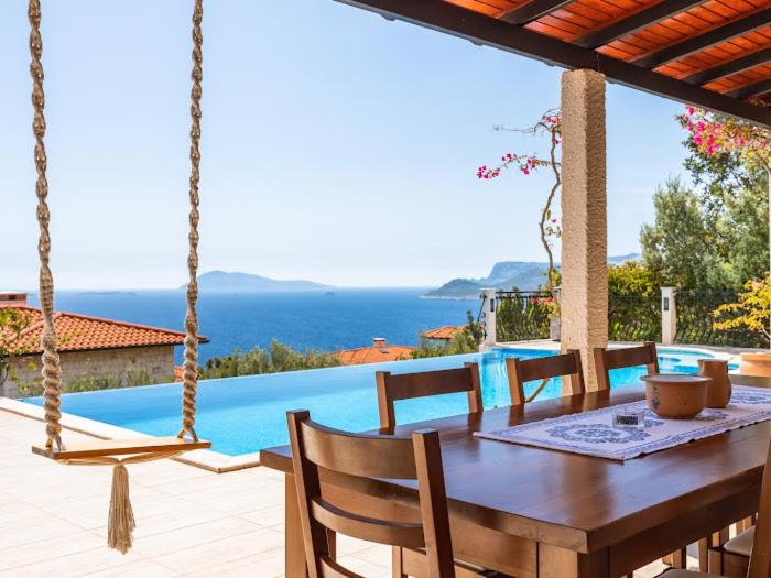 a wooden dining table with chairs and a pool at VILLA SCARLETT in Kaş