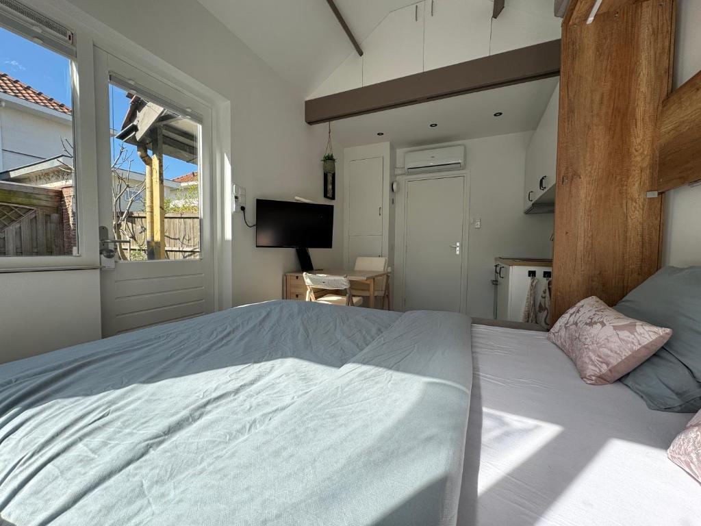 een slaapkamer met een groot bed en een raam bij Tiny Home in Aalsmeer