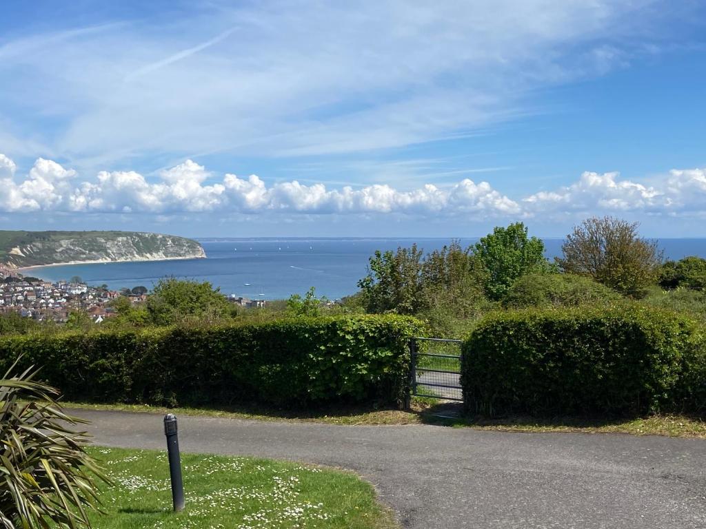 a road with a fence and a view of the ocean at Stunning Caravan on Swanage Bay View Holiday Park in Swanage