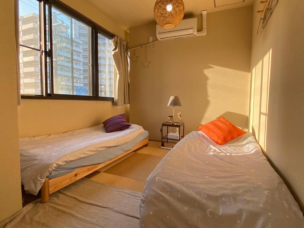 um quarto com 2 camas e uma janela em Bonfire Hostel Osaka em Osaka