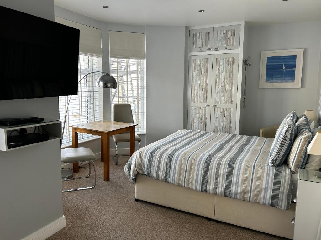 a bedroom with a bed and a desk and a television at Wenden Guest House in Newquay