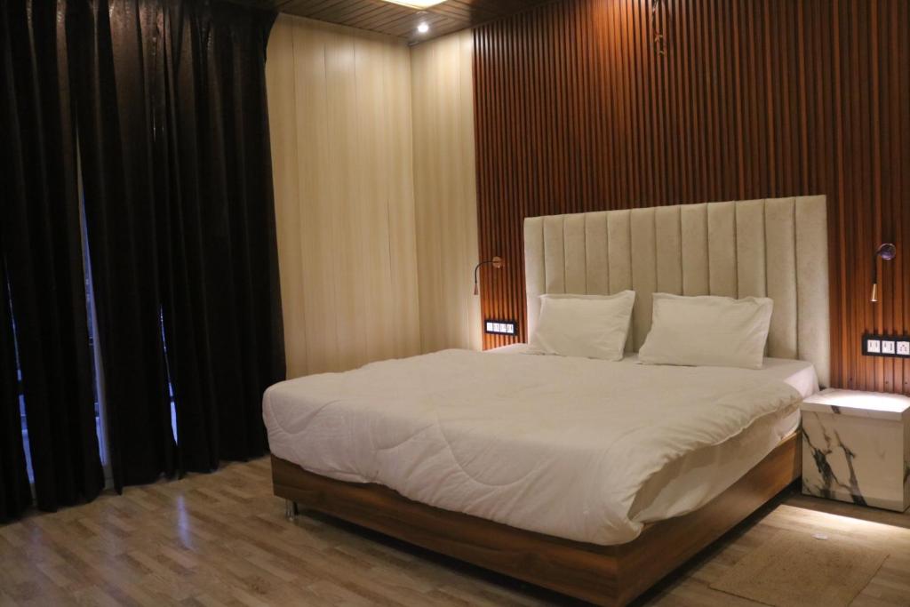 1 dormitorio con 1 cama grande con sábanas y almohadas blancas en AVTARA RESORT RISHIKESH, en Rishīkesh