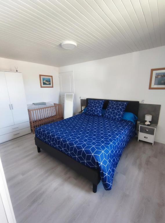 une chambre avec un lit avec une couette bleue dans l'établissement Agréable Maison, toute équipée, proche du lac d'Arjuzanx, à Morcenx