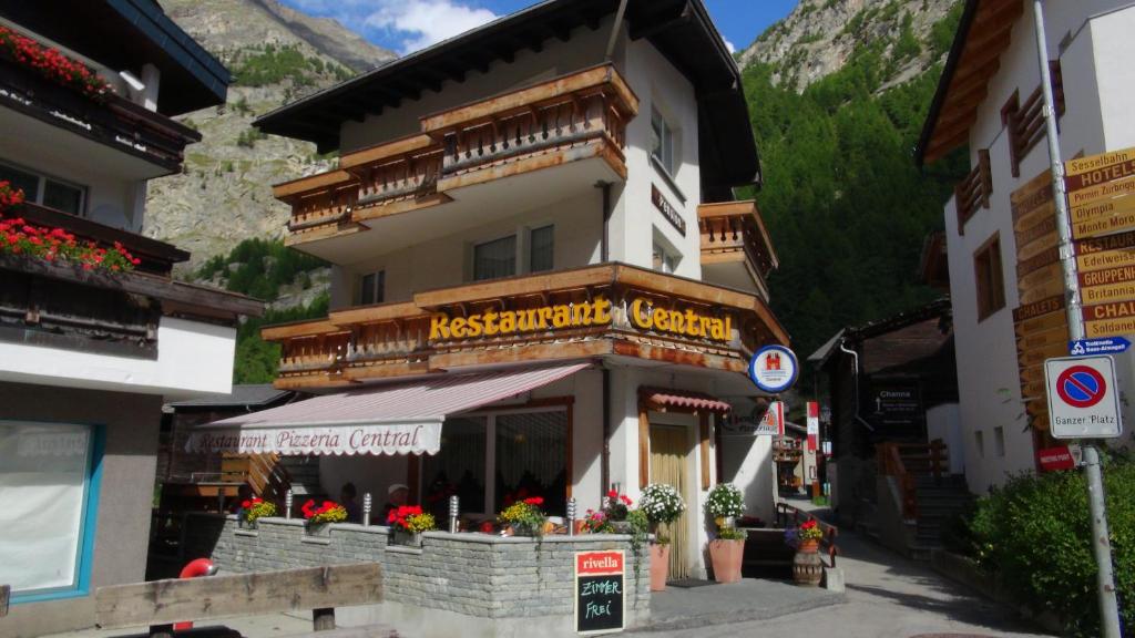 a building with a restaurant with flowers in front of it at Pension Central in Saas-Almagell