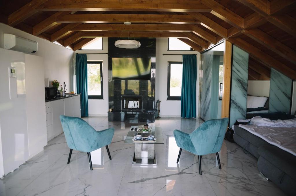 a living room with two blue chairs and a table at Casa moderna in Sinteu - intersectia intre modern si linistea naturii in Huta Voivozi
