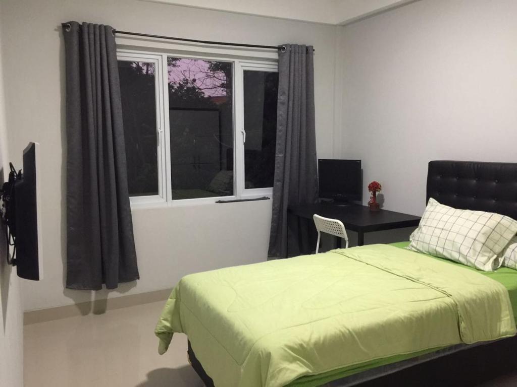 um quarto com uma cama, uma secretária e uma janela em Surya Maju Landmark Residence em Bandung