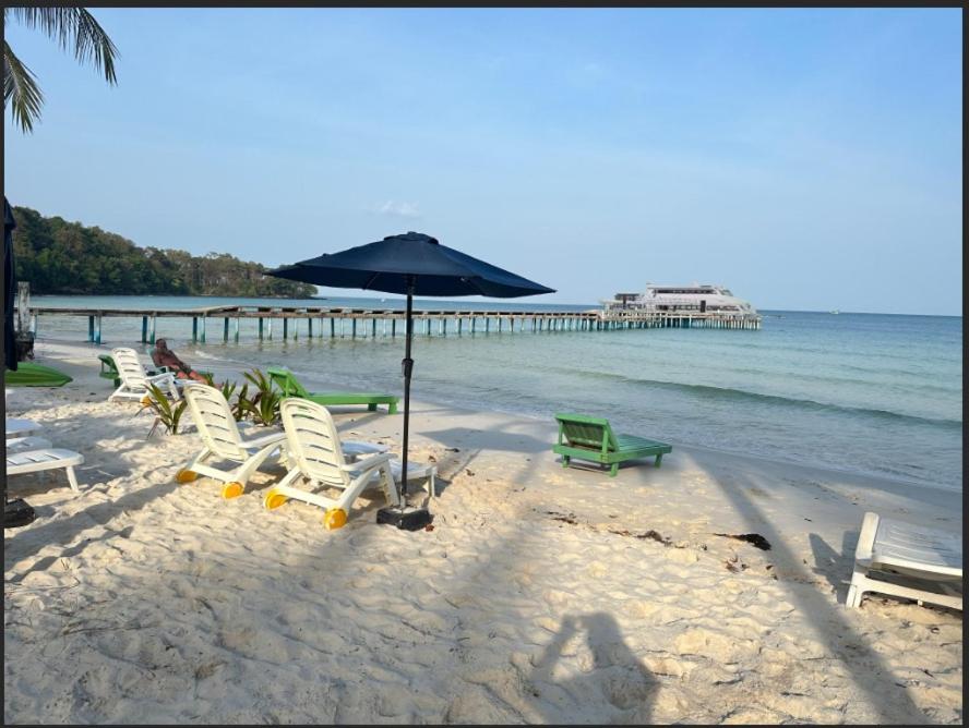 een groep stoelen en een parasol op een strand bij Koh RhongSunshine Resort2 in Phumĭ Kaôh Rŏng