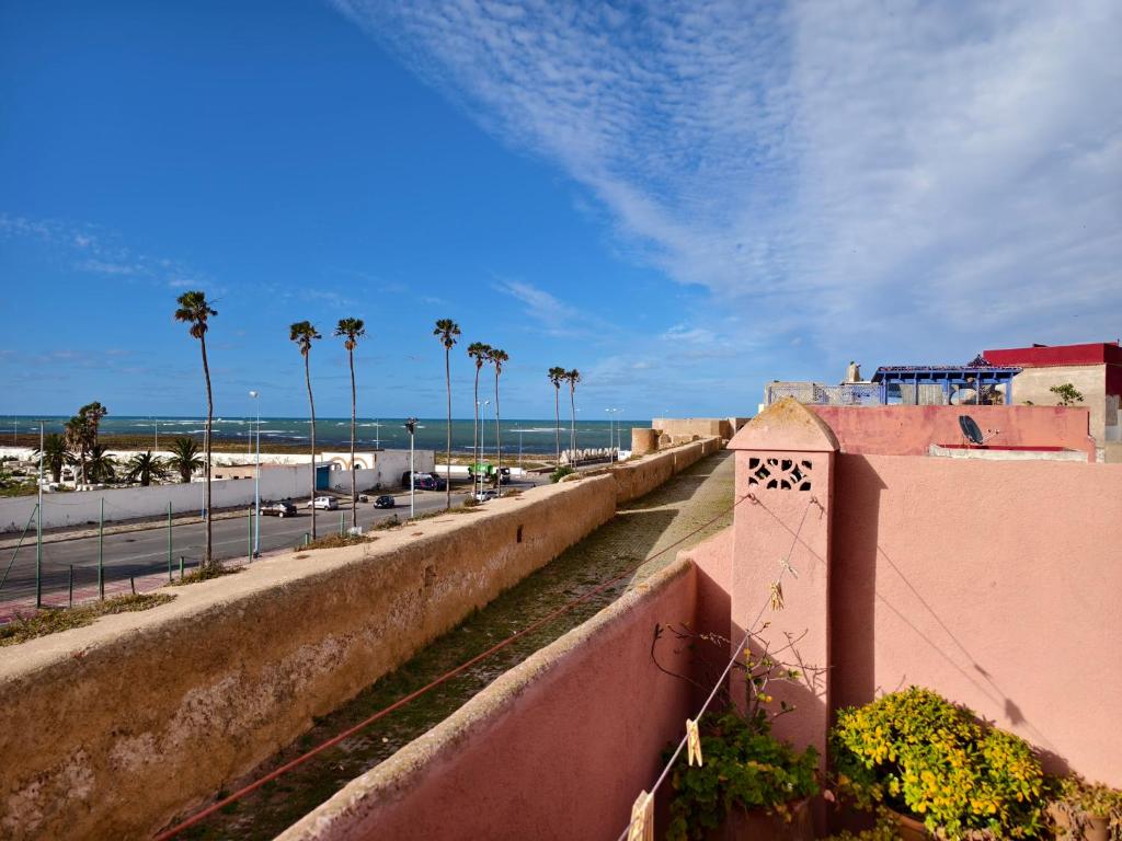 una pared junto a una playa con palmeras en Dar Nadia, en El Jadida