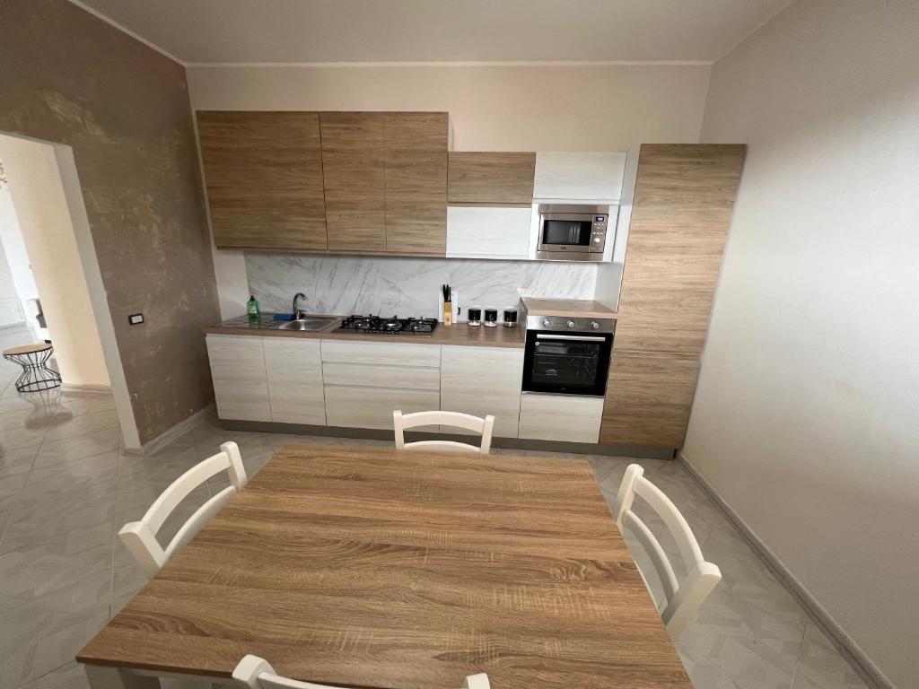 una cucina con tavolo in legno e armadietti bianchi di Casa vacanza La casa delle Onde a Torrenova