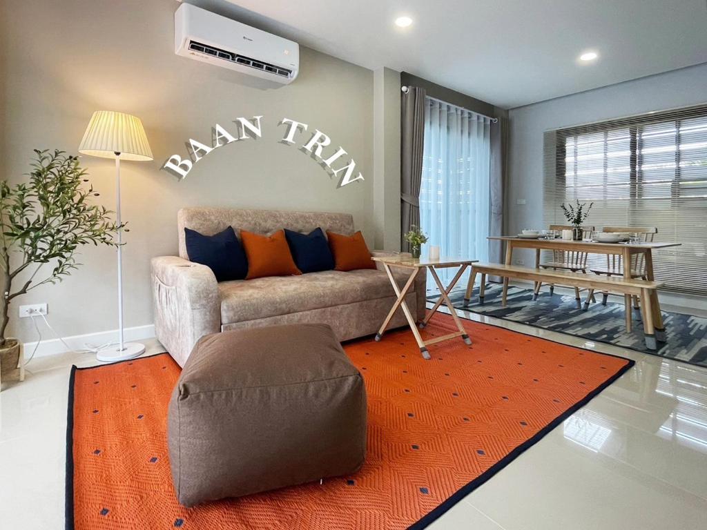 Baan Trin(บ้านตฤณ) في شيانج راي: غرفة معيشة مع أريكة وسجاد برتقالي