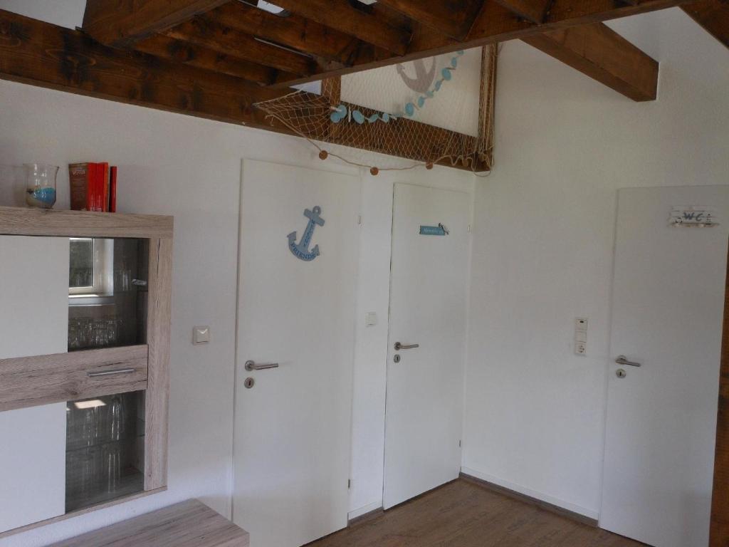 Cette chambre dispose de deux portes blanches et d'une fenêtre. dans l'établissement Freistehendes Friesenhaus Heimathafen, à Halbemond