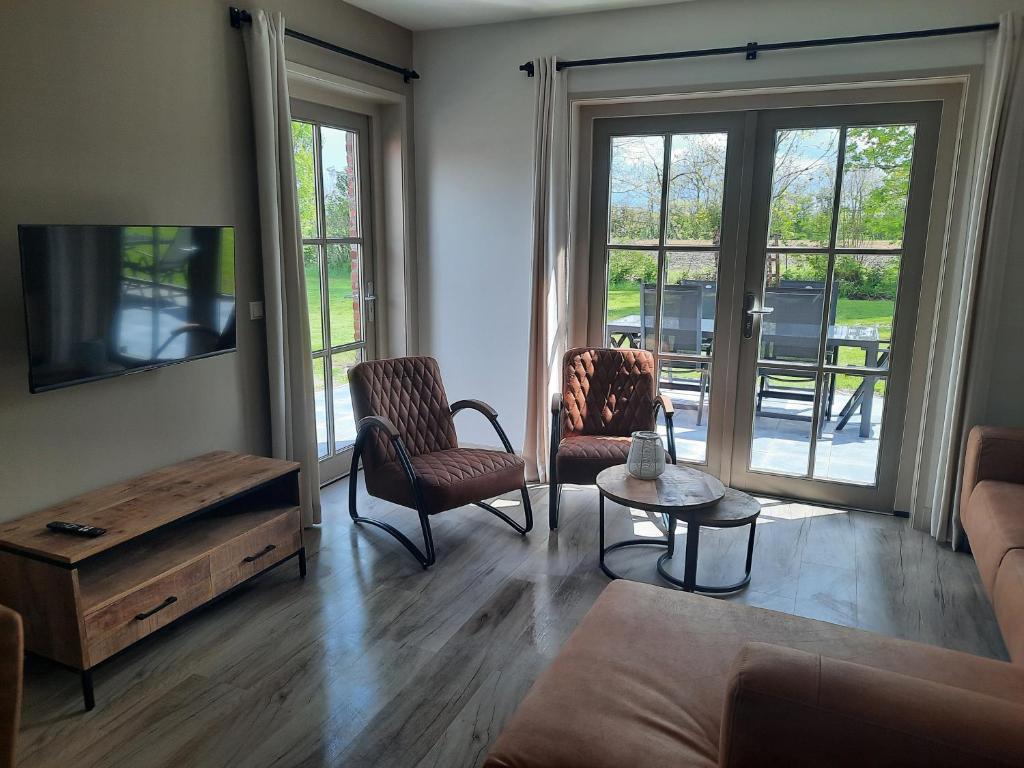 een woonkamer met een bank, stoelen en een tafel bij zomerhuisje by the sea in Zoutelande