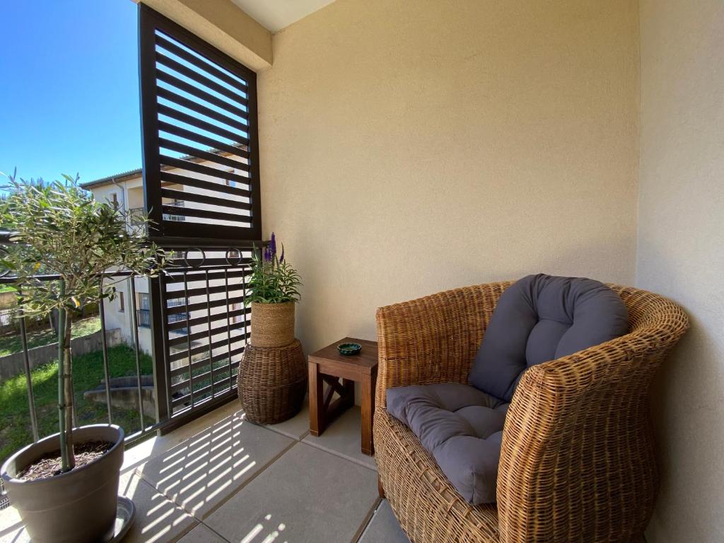 a wicker chair sitting on a balcony with a window at Emplacement idéal, garage privé, piscine intérieure in Uzès