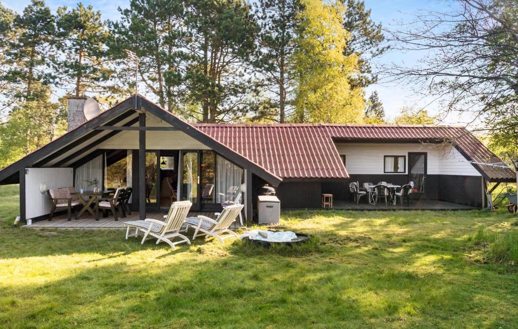 a small house with a deck and chairs in the yard at 3 Bedroom Cozy Home In Rdby in Rødby