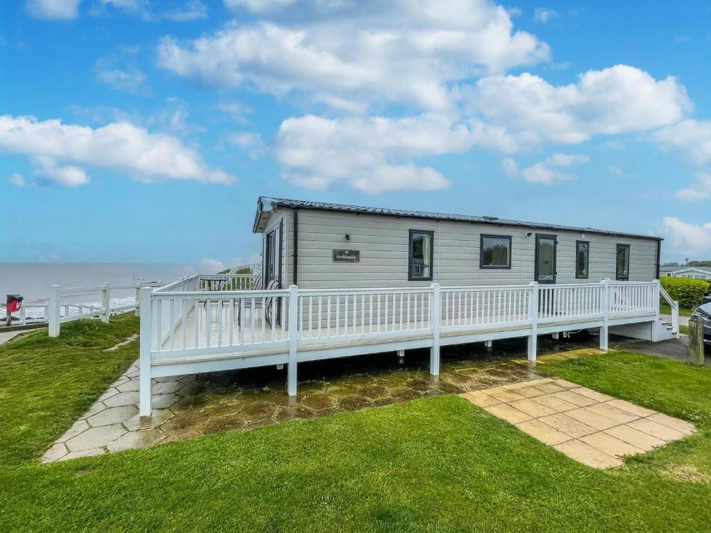 a mobile home with a white deck and the ocean at Beautiful Caravan With Stunning Sea Views At Haven Hopton Ref 80001h in Great Yarmouth