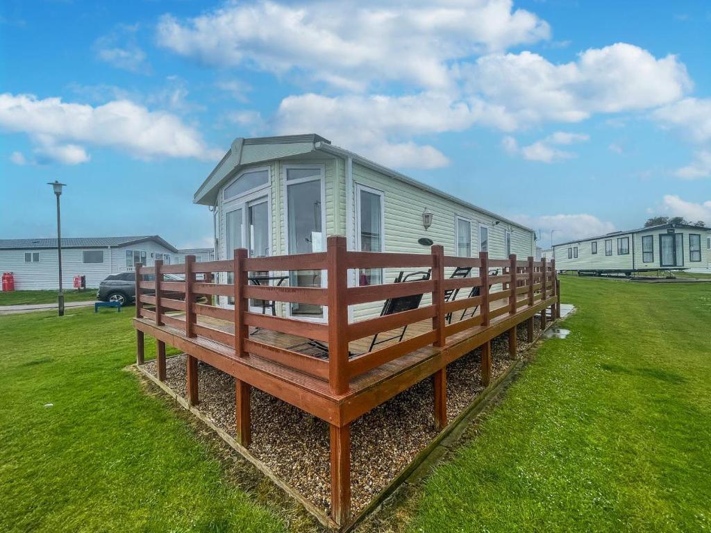 a house with a large wooden bench in the grass at Lovely 6 Berth Caravan With Decking, Wifi And Onsite Beach Access Ref 68004cl in Lowestoft