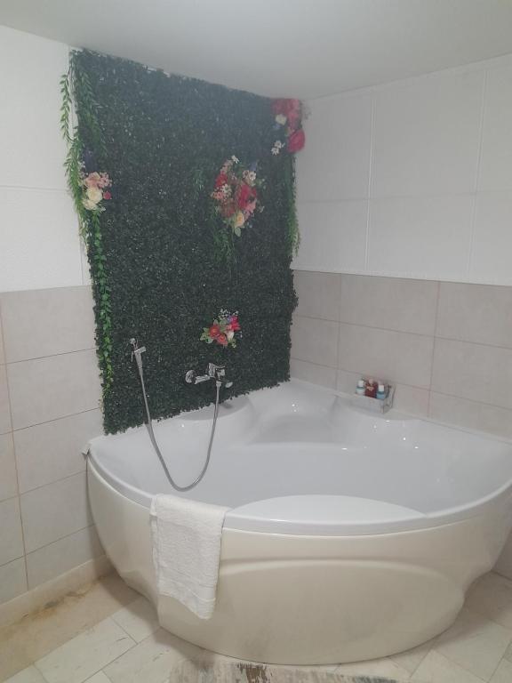 La salle de bains est pourvue d'une baignoire blanche et de fleurs roses. dans l'établissement Apartman Tomic, à Brčko