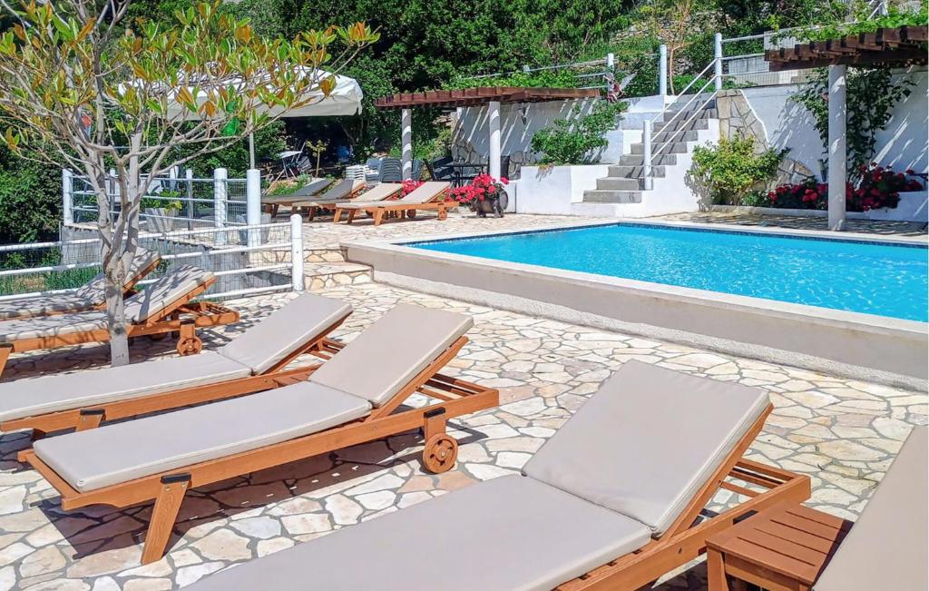 a pool with lounge chairs and a swimming pool at Nice Apartment In Mimice With Outdoor Swimming Pool in Mimice