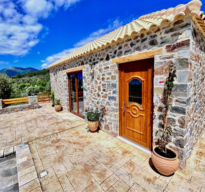 een stenen huis met een houten deur en een patio bij Cassiopea Guest House Evia Greece in Nerotriviá