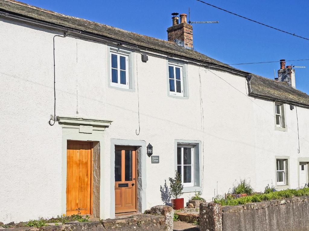 a white house with a wooden door at Earsdon Cottage in Ireby