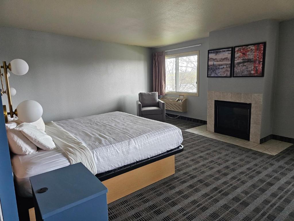 a hotel room with a bed and a fireplace at AmericInn by Wyndham Oscoda Near AuSable River in Oscoda