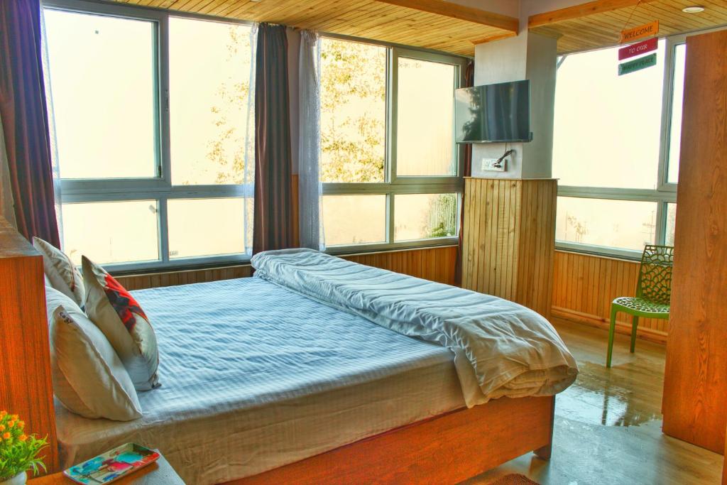 a bedroom with a bed with windows in it at Cozy Homestay & Cafe in Darjeeling