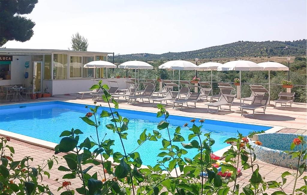 a swimming pool with chairs and umbrellas on a resort at 1 Bedroom Gorgeous Apartment In Vieste in Vieste