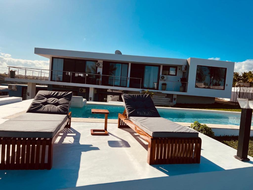 une maison avec une piscine et deux chaises longues dans l'établissement Villa Luasah, à Vila Praia Do Bilene