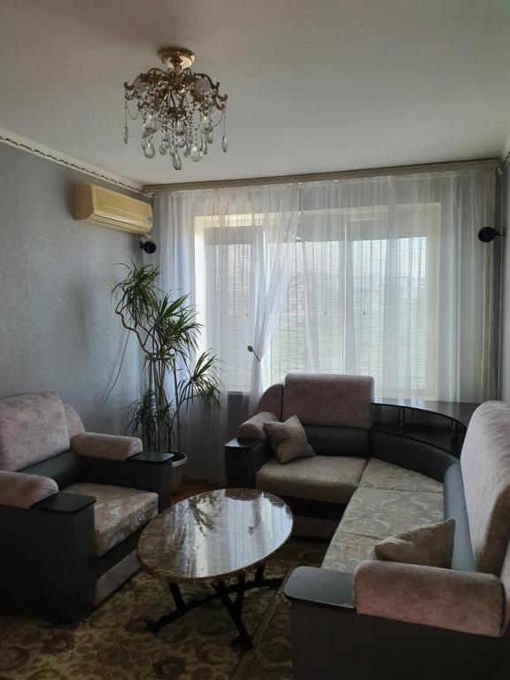 sala de estar con sofás, mesa y lámpara de araña en Уютная квартира в центре города., en Aktau