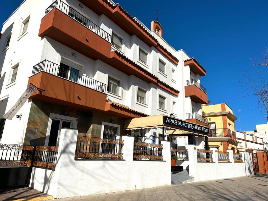 Un grand bâtiment blanc avec balcon se trouve dans une rue. dans l'établissement APARTAHOTEL DOÑA REYES, à Chipiona