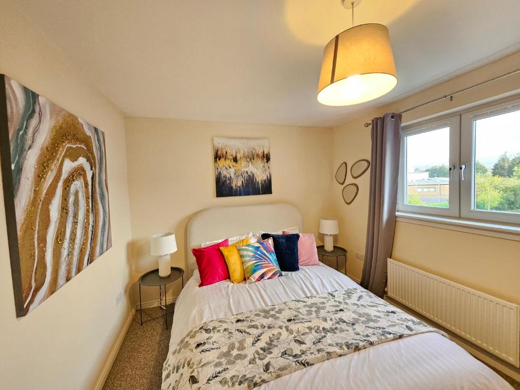 um quarto com uma cama com almofadas coloridas em Sensational Stay Apartments @ Torwood em Edinburgo