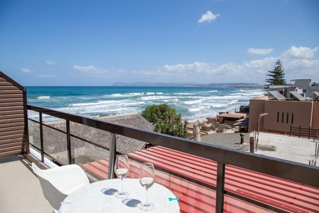 balkon ze stołem i krzesłami oraz oceanem w obiekcie Nefeli Rooms w mieście Agia Marina Nea Kydonias