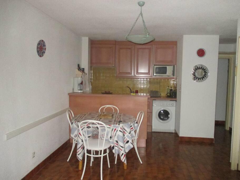 une cuisine avec une table et des chaises dans une pièce dans l'établissement Les logis de Magali les Zodiacs, terrasse, plage à 600m, à Argelès-sur-Mer