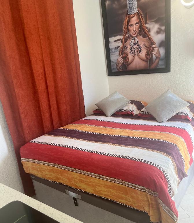 - un lit dans une chambre avec une photo sur le mur dans l'établissement BEGOOD'IZ naturiste Studio indépendant au calme au coeur du village, au Cap d'Agde