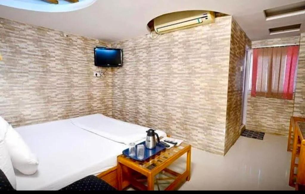 a bedroom with a bed and a tv on a brick wall at Ganpati Hotel in Bhopal