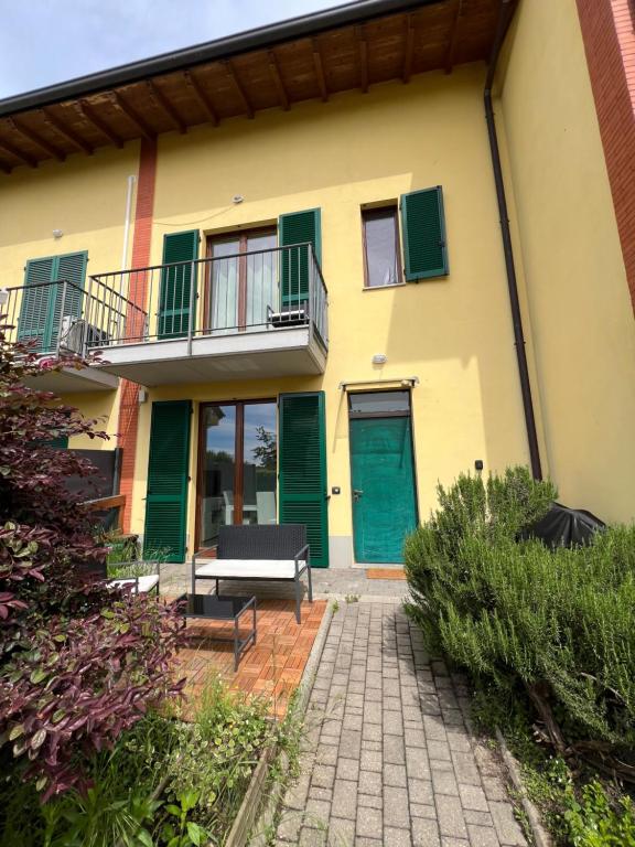 a yellow house with green doors and a patio at Casa Oasi Sette Laghi in Mercallo