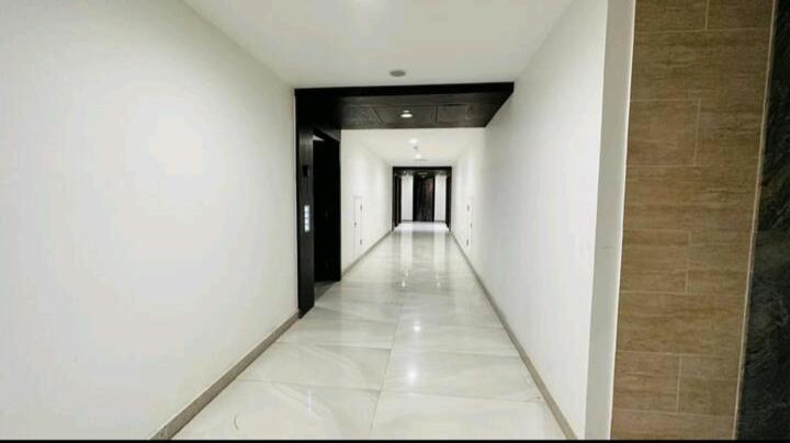 einen leeren Flur mit weißen Wänden und einen Flur mit schwarzen Türen in der Unterkunft Premium 1BR DHA Phase 5 in Lahore