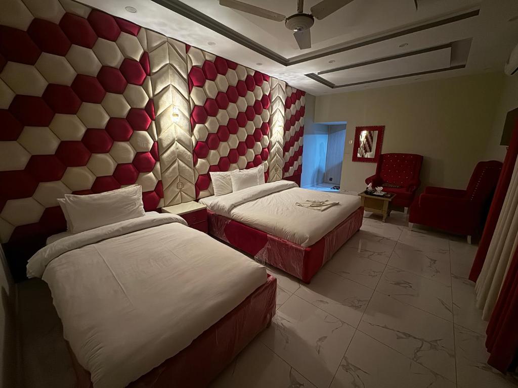 una habitación de hotel con 2 camas y una silla en Decent Lodge Guest House F-10, en Islamabad