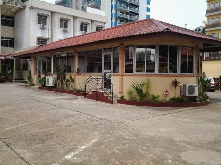 ein Gebäude mit Fenstern und Pflanzen auf einem Parkplatz in der Unterkunft Bau rivage hotel in Akwa