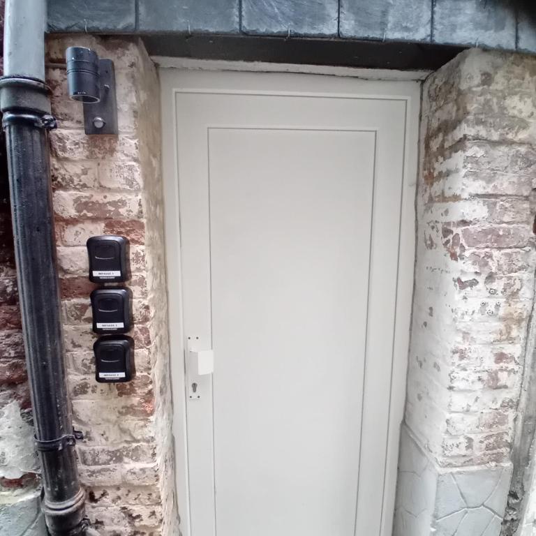 a white door on a brick wall with a gas meter at Impasse 1 in Fosses-La-Ville