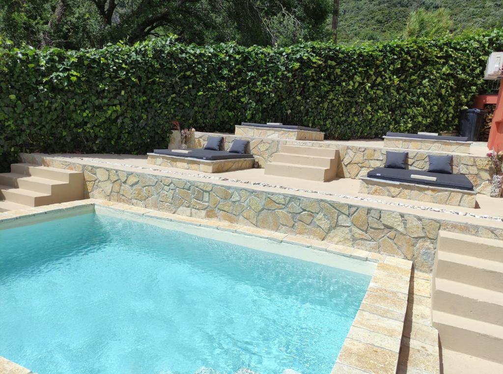 Skriperón的住宿－GKK House private swimming pool luxury house，一个带椅子和石墙的游泳池