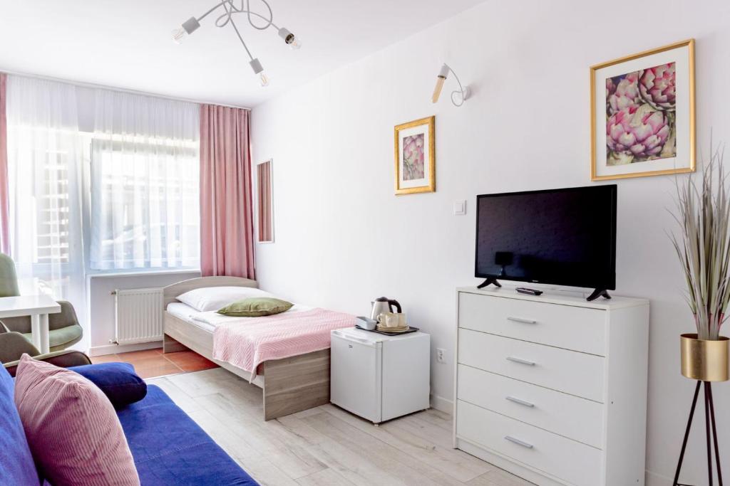 a white bedroom with a bed and a tv at Willa Bliźniak 2 - Wyżywienie wliczone w cenę in Karwia