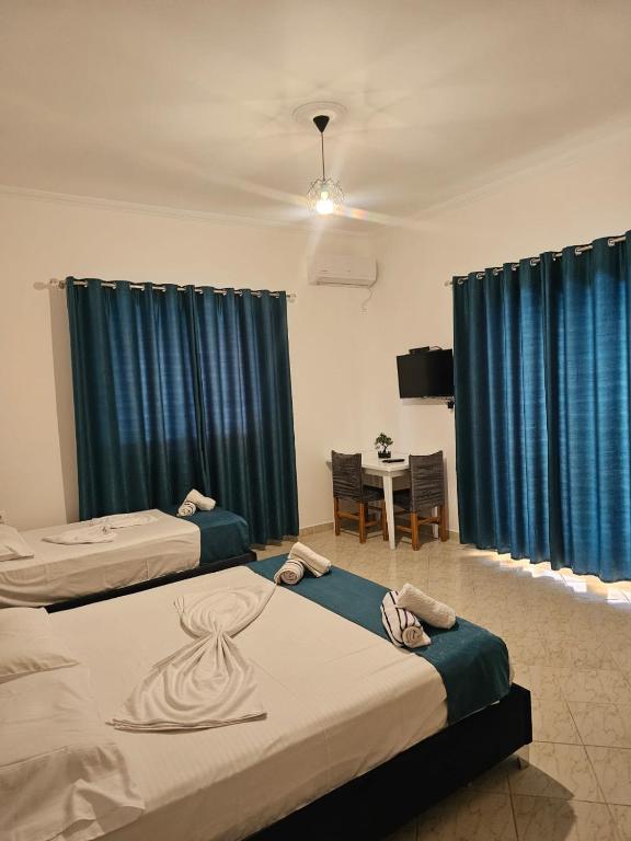two beds in a room with blue curtains at DEA Room 1 in Sarandë