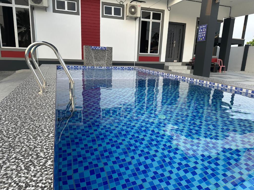 a large swimming pool with blue tiles in a building at Tokmabah Homestay in Ketereh