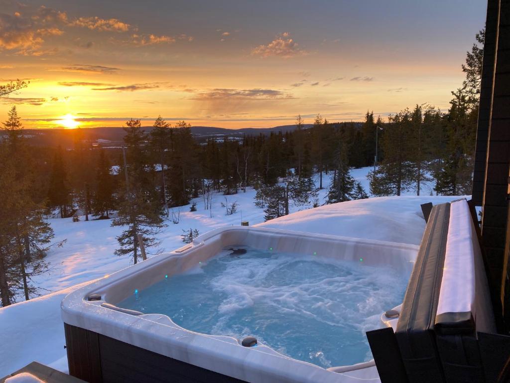 una bañera de hidromasaje en la nieve con la puesta de sol en Näköalahuvila Pikku-Syötteen Helmi, en Syöte