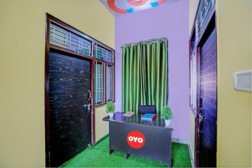 OYO Flagship Midtown Guesthouse في Jhājhar: غرفة مع باب وطاولة مع لاب توب