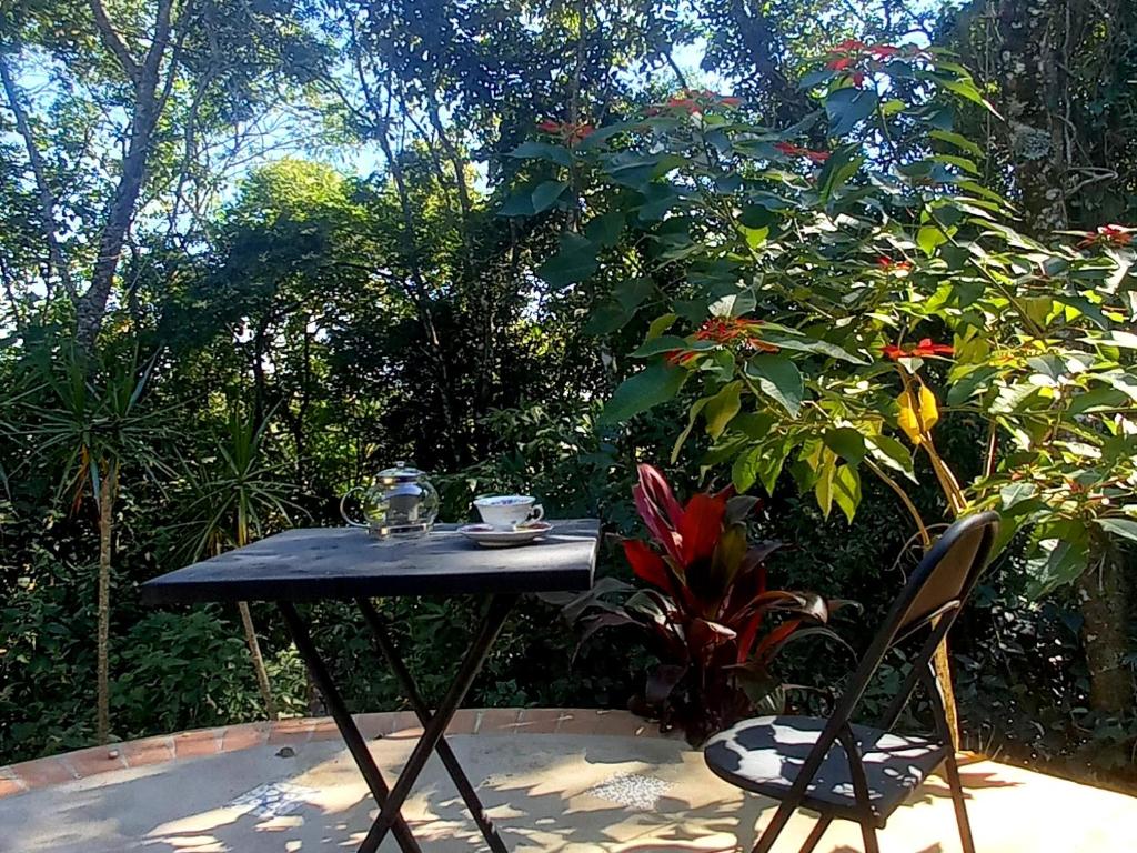 uma mesa preta e duas cadeiras num jardim em Casinha acolhedora da mata - Rota do Vinho em São Roque