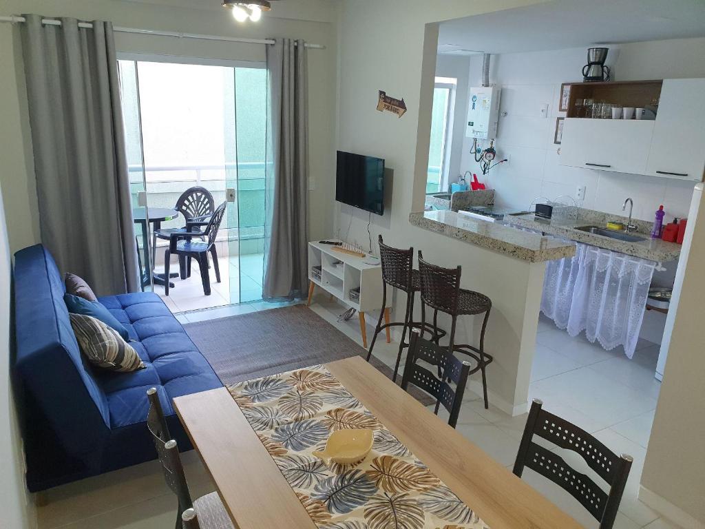 uma sala de estar com um sofá azul e uma cozinha em AP encantador na Praia do Forte! (208) em Cabo Frio