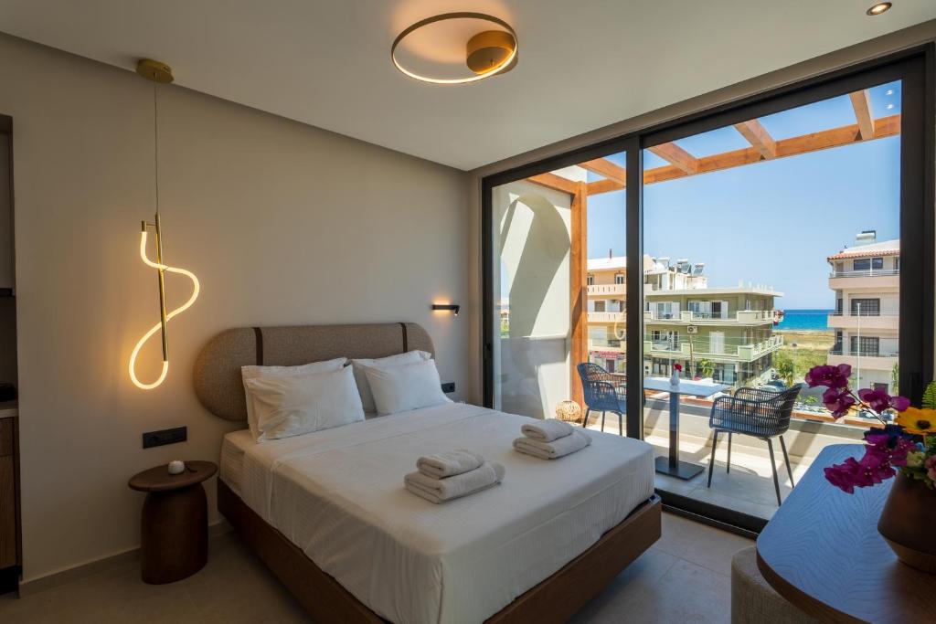 Vaya Suites by Omilos Hotels في أمودارا هيراكليو: غرفة نوم مع سرير وإطلالة على المحيط