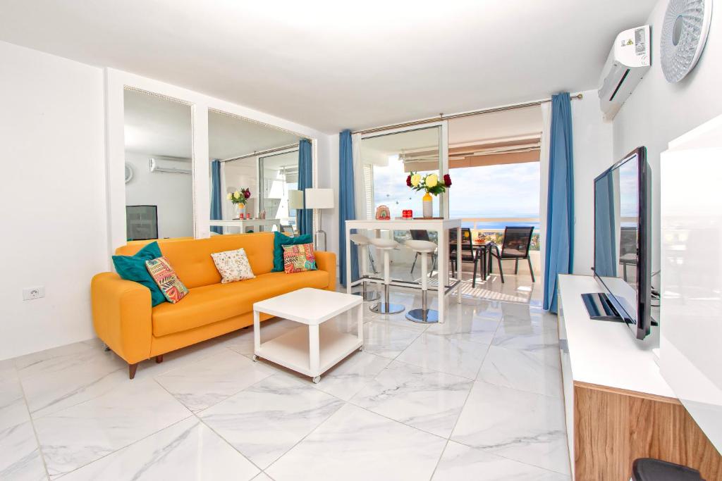 een woonkamer met een gele bank en een tafel bij Colourful Bright Centred Apt. with Ocean View in Playa Fañabe